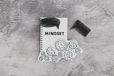 positivity and law of attraction conceptual image, notepad with Mindset text with different thought bubbles and gearwheel mechanism next to itの写真素材