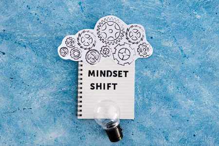 positivity and law of attraction conceptual image, notepad with Mindset Shift text with light bulb...