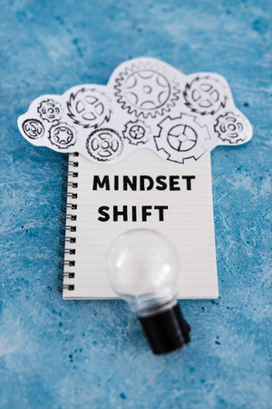 positivity and law of attraction conceptual image, notepad with Mindset Shift text with light bulb...