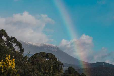 Tasmanian landscape with green hills and mountains with rainbow and blue skyの写真素材