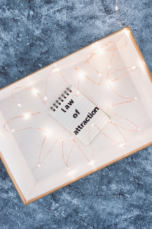 law of attraction and positive mindset conceptual image, box as metaphor of the mind with Law Of Attraction notepad surrounded by fairy lightsの写真素材