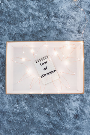 law of attraction and positive mindset conceptual image, box as metaphor of the mind with Law Of Attraction notepad surrounded by fairy lightsの写真素材