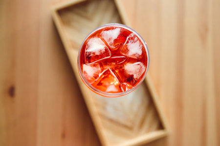 orange cocktail in tall glass on wooden table with golden light shining from nearby window, concept...