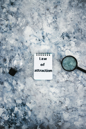 law of attraction notepad with text next to light bulb and magnifying glass symbol of introspection...