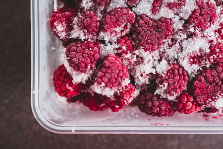 simple food ingredients concept, close-up of frozen raspberries with icicles on them
