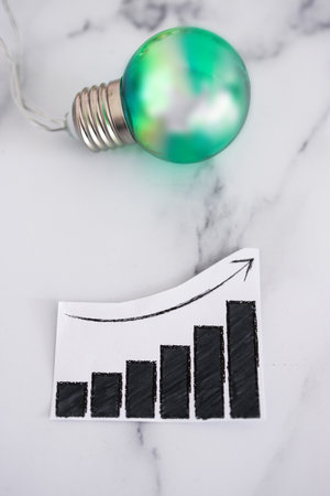 ecology and green ideas for the environment conceptual image, green light bulb next to positive growth stats graphの写真素材