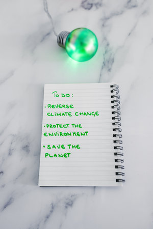 ecology and green ideas for the environment conceptual image, green light bulb next to to do list to save the planetの写真素材
