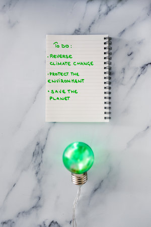 ecology and green ideas for the environment conceptual image, green light bulb next to to do list to save the planetの写真素材