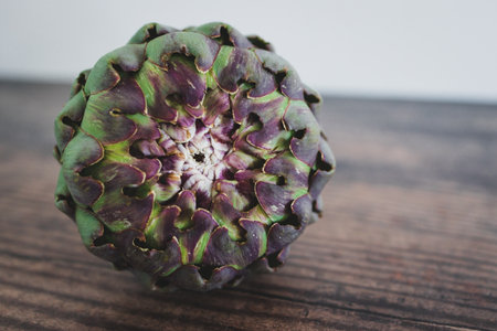 simple food ingredients concept, freshly harvested artichoke on wooden kitchen counter