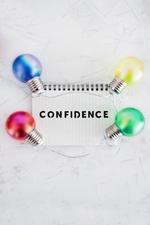 positive attitiude concept, confidence text on notepad surrounded by colorful light bulbs symbol of ideasの写真素材