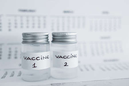 vaccine and immunisation against the pandemic, ampoules with Vaccine 1 and Vaccine 2 labels side by side next to 2021 yearly calendarの写真素材