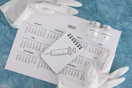 vaccine against the pandemic, 2021 calendar with syringe sketch on notepad and disposable gloves on itの写真素材