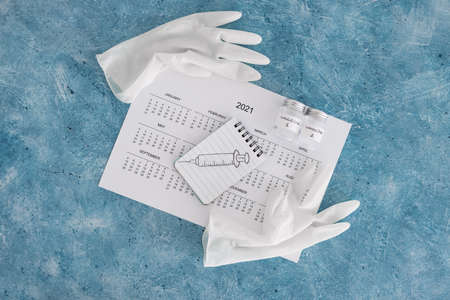 vaccine against the pandemic, 2021 calendar with syringe sketch on notepad and disposable gloves on itの写真素材