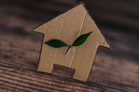green home and energy efficiency conceptual image, ecological house icon with leaves on it on wooden backgroundの写真素材