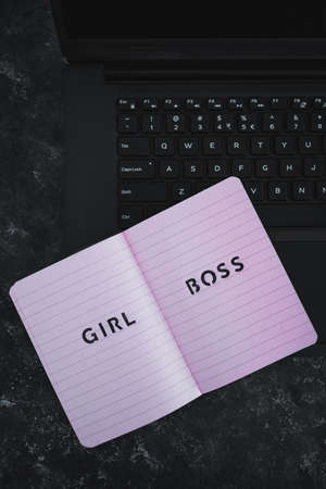 equal opportunities concept, Girl Boss text on top of pink notebook on laptop keyboard on black backgroundの写真素材