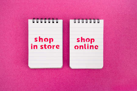 competition and retail industry conceptual image, shop in store vs shop online texts on notepads side by sideの写真素材