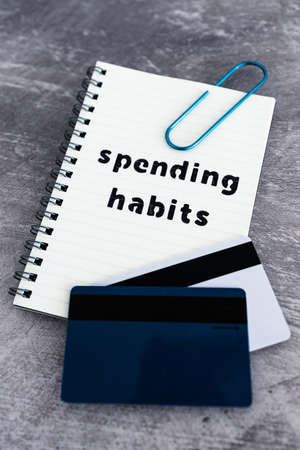 spending habits text on notepad with payment cards next to it, money and consumer behaviour...