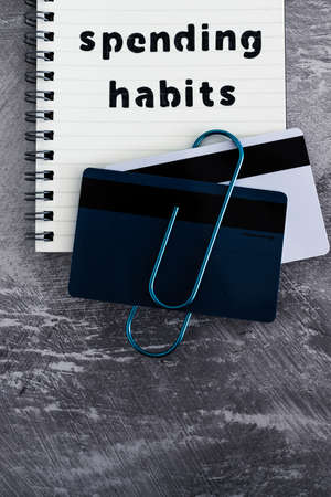 spending habits text on notepad with payment cards next to it, money and consumer behaviour conceptual imageの写真素材