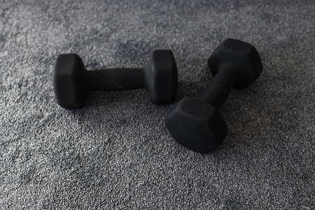 fitness and exercising at home concept, couple of black dumbbells on carpet indoorの写真素材