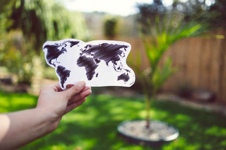 ecology and sustainable development concept, hand holding world map under the sun with garden bokeh...