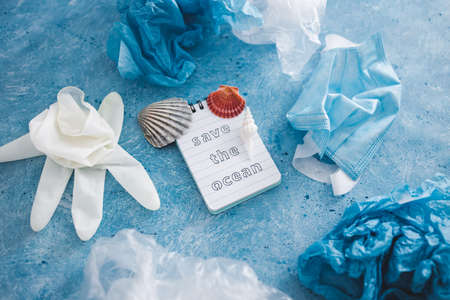 save the ocean text on blue bakground with sea shells and plastic garbage symbol of environmental pollution to fix, ecology and respect for the planet conceptual imageの写真素材