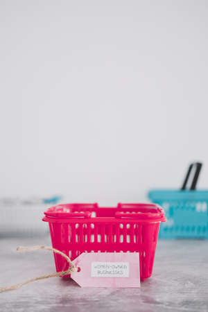 women-owned businesses tag with pink shopping basket among competitor blue ones, supporting equality and equal opportunitiesの写真素材
