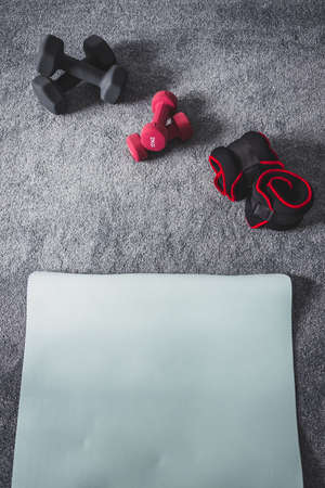 home gym with mixed fitness items including ankle weights and different sets of dumbbells on the floorの写真素材
