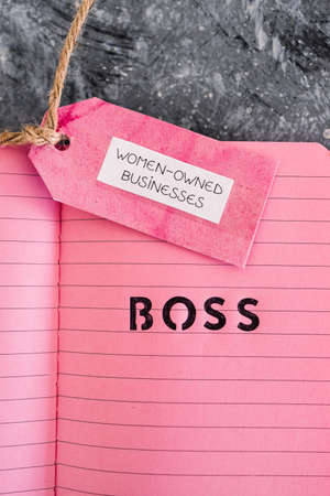 women-owned business tag with girl boss text on pink notepad, supporting equality and equal...