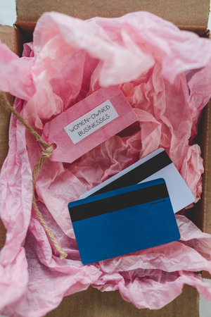 women-owned businesses tag and credit cards inside online order delivery parcel, supporting equality...