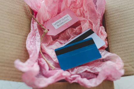 women-owned businesses tag and credit cards inside online order delivery parcel, supporting equality...