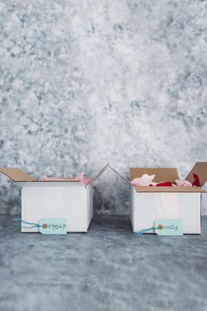 Cheap vs Costly product price tags in two delivery parcels next to each other symbol of options for...