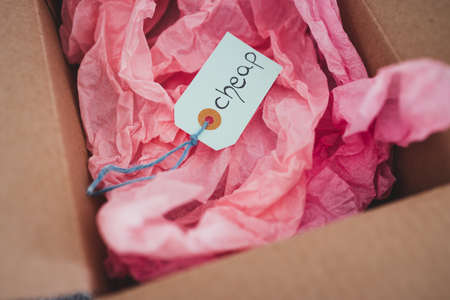 Cheap product price tag in delivery parcel, money and consumer behaviour concept