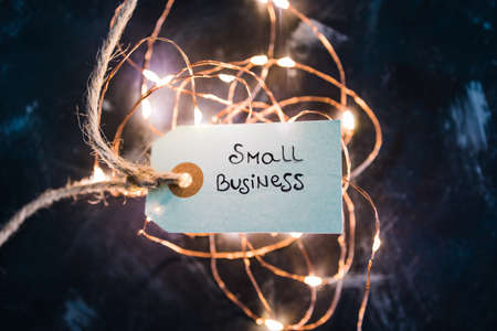 product tags with small business text surrounded by fairy lights, concept of customer behaviour and...