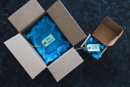 product tags with small business vs big brand texts inside of bigger and smaller delivery parcels, concept of customer behaviour and supporting small local businessesの写真素材