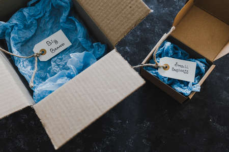 product tags with small business vs big brand texts inside of bigger and smaller delivery parcels, concept of customer behaviour and supporting small local businessesの写真素材