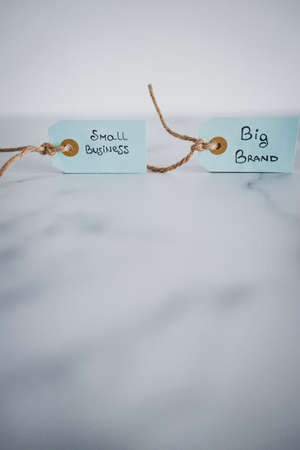 product tags with small business vs big brand texts side by side sho at shallow depth of field,...