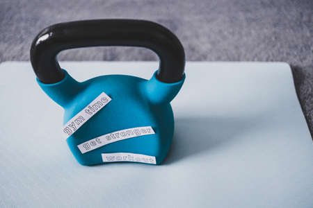 home gym and exercising in your spare time conceptual image, kettlebell with Gym Time Workout and Get Stronger message on yoga mat on bedroom floorの写真素材