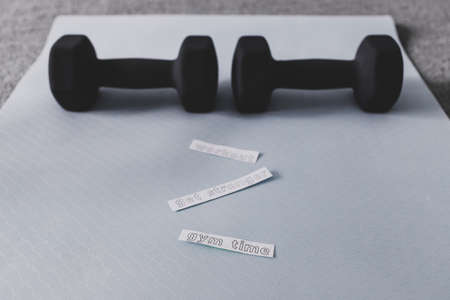 home gym and exercising in your spare time, dumbbell on yoga mat on bedroom floor with Get Stronger Workout and Gym Time messagesの写真素材
