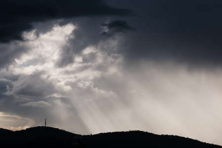 thick stormy clouds over the mountains with intense sun rays peaking through and contrasty light...
