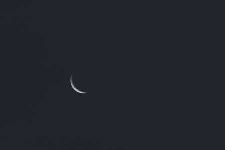 crescent moon in the night sky shot with telephoto lens with subtle crushed black editingの写真素材
