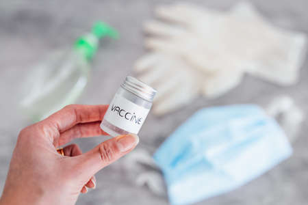 covid-19 vaccine race and life after the pandemic, hand holding vaccine ampooule with disposable...