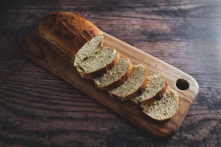 vegan homemade bread made with soy milk and herbs on wooden cutting board on rustic wooden...