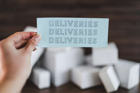 shipping industry and online shopping concept, group of white delivery parcels with hand holding Deliveries Deliveries Deliveries text in front of themの写真素材