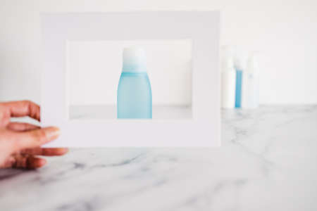 low tox and non-toxic natural beauty products conceptual image, hand hiolding a frame around a blue...