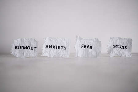 Mental health text on notepad surrounded by Fear Anxiety Stress and Burnout words on scrunched up pages, psychology  and emotional wellness conceptの写真素材