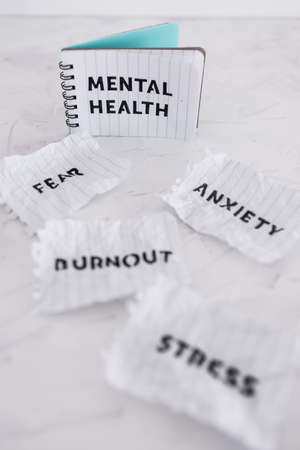 Mental health text on notepad surrounded by Fear Anxiety Stress and Burnout words on scrunched up pages, psychology  and emotional wellness conceptの写真素材