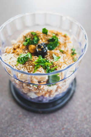 food processor with falafels ingredients inside including chickpeas onion cilantro garlic and sesame seeds, concept of simple natural healthy ingredientsの写真素材