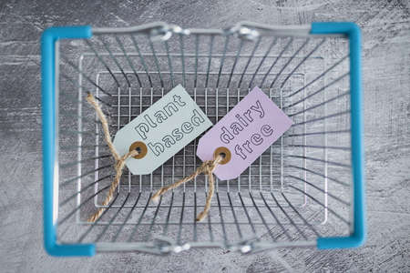 plant-based and dairy-free product tags on top of grocery shopping basket, concept of healthy nutrition and ethical dietary choicesの写真素材