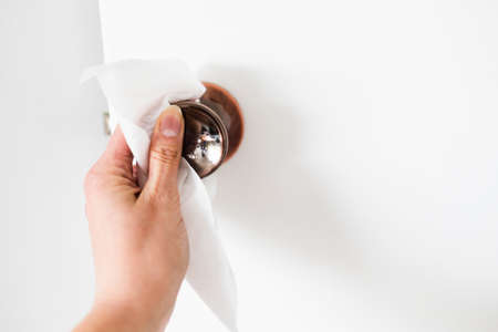 disinfecting surfaces from bacteria or viruses, hand cleaning door knob with disinfectant wet wipe...