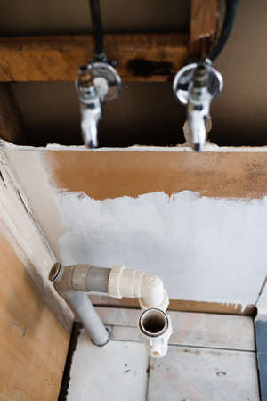 laundry room renovation with plaser walls interior exposed with taps and copper pipes, concept of home renovations and tradesman workの写真素材
